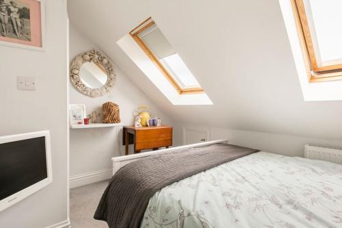 a bedroom with a bed and a flat screen tv at Hideaway Cottage - seaview room with shared bathroom in Sandgate