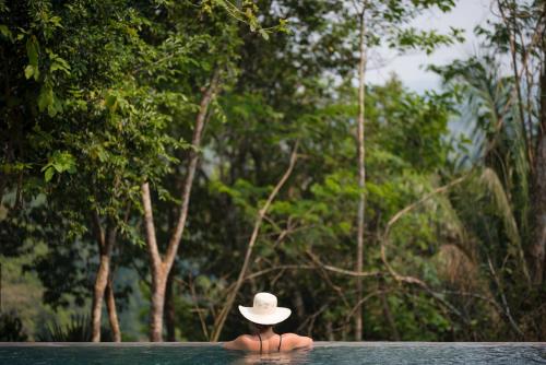 a person with a hat sitting in a pool at Sweet Songs Jungle Lodge in San Ignacio