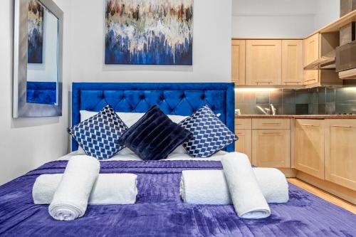 ein Schlafzimmer mit einem lila Bett mit Kissen in der Unterkunft Immaculate 1-Bed Studio in London in London