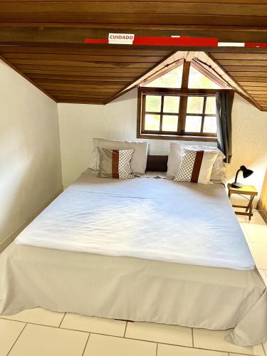 a large white bed in a room with a window at Hospedagem Braga - acomodação domiciliar in Cunha