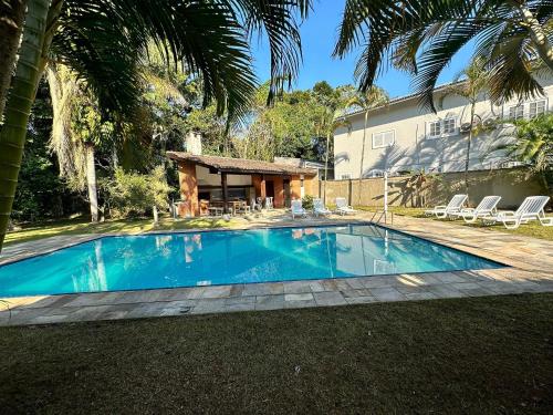 - une piscine en face d'une maison dans l'établissement Casa com Piscina e Churrasqueira na Riviera em Bertioga, à Riviera de São Lourenço