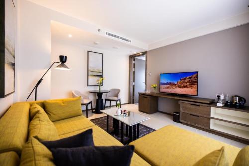 a living room with a yellow couch and a flat screen tv at Almorqqabat Rooms in Dubai
