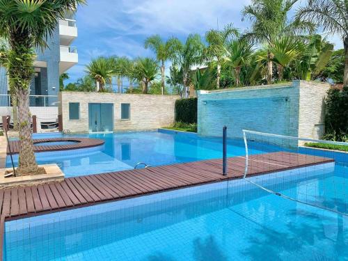 a swimming pool in a resort with palm trees at Apto Moderno e Completo a 50m da Praia in Bertioga