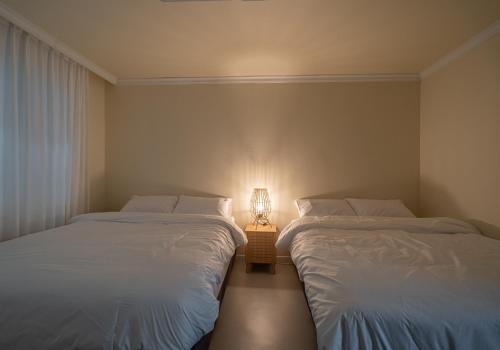 two beds in a room with a lamp between them at Osondoson Stay in Seoul