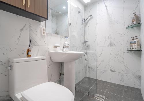a white bathroom with a toilet and a sink at Osondoson Stay in Seoul