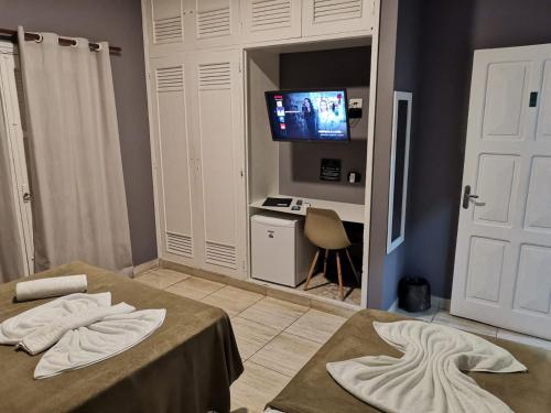 um quarto com duas camas e uma televisão na parede em POUSADA NOSSO LAR no Guarujá