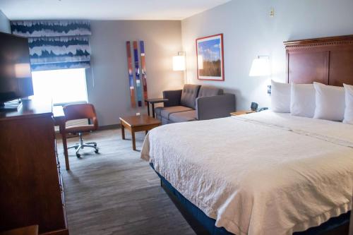 a hotel room with a large bed and a couch at Hampton Inn Marion in Marion
