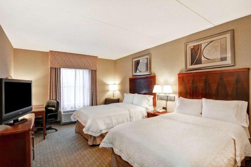 ein Hotelzimmer mit 2 Betten und einem Flachbild-TV in der Unterkunft Hampton Inn Lewisburg in Lewisburg