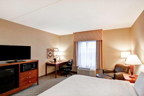 a hotel room with a bed and a flat screen tv at Hampton Inn Lewisburg in Lewisburg