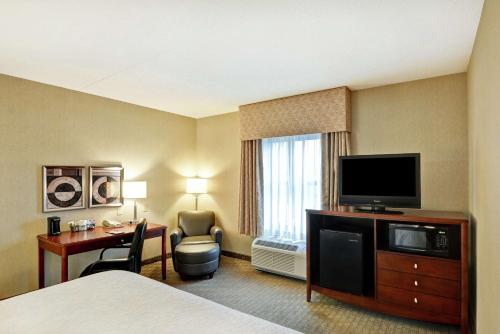 a hotel room with a bed and a desk and a television at Hampton Inn Lewisburg in Lewisburg