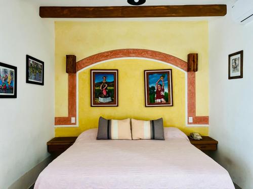 a bed in a room with paintings on the wall at Los Arrayanes in Oaxaca City