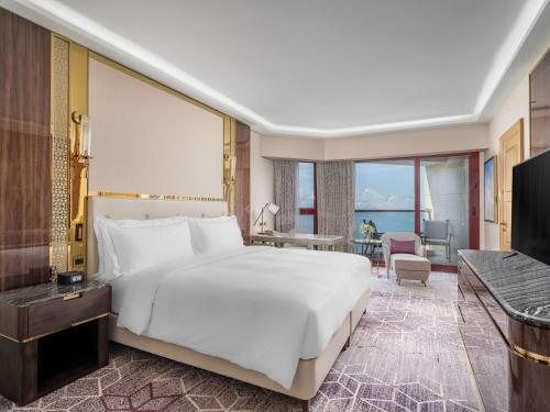 een slaapkamer met een groot wit bed en een bureau bij Jeddah Hilton in Jeddah