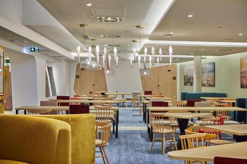 un comedor con mesas, sillas y lámparas de araña en Hampton By Hilton Barcelona Fira Gran Via en Hospitalet de Llobregat