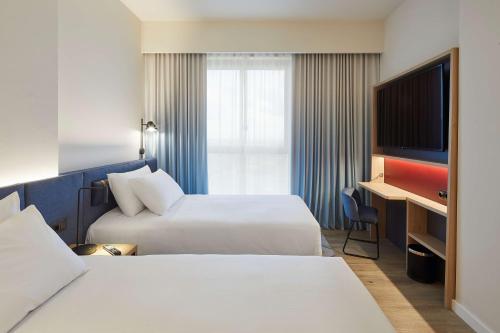 a hotel room with two beds and a television at Hampton By Hilton Barcelona Fira Gran Via in Hospitalet de Llobregat