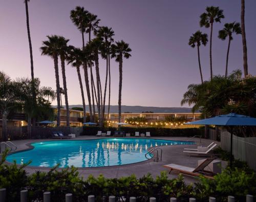 a swimming pool with palm trees in a resort at The Leta Santa Barbara Goleta, Tapestry Collection by Hilton in Santa Barbara