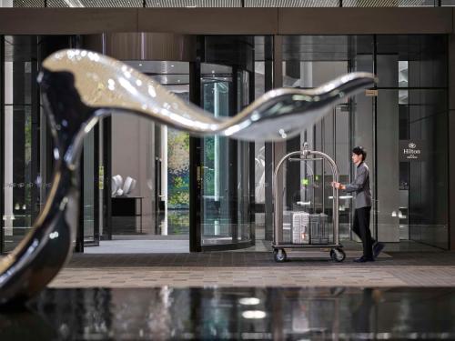 a man with a luggage cart in front of a building at Hilton Zhuji in Zhuji