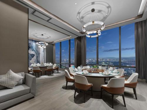 a dining room with a table and chairs and large windows at Hilton Zhuji in Zhuji