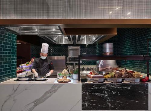 two chefs in a kitchen preparing food in a kitchen at Hilton Zhuji in Zhuji