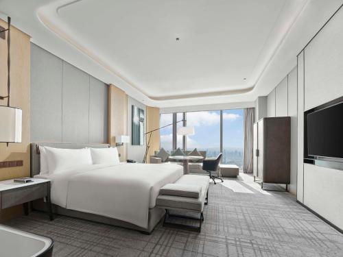 a bedroom with a large white bed and a desk at Hilton Zhuji in Zhuji