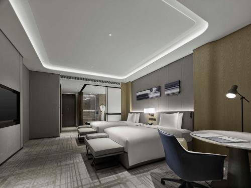 a hotel room with a bed and a desk and chairs at Hilton Zhuji in Zhuji