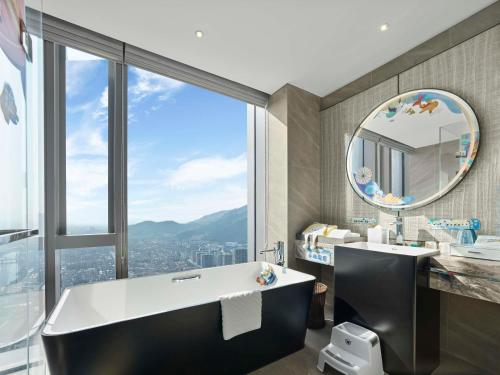 a bathroom with a tub and a sink and a mirror at Hilton Zhuji in Zhuji