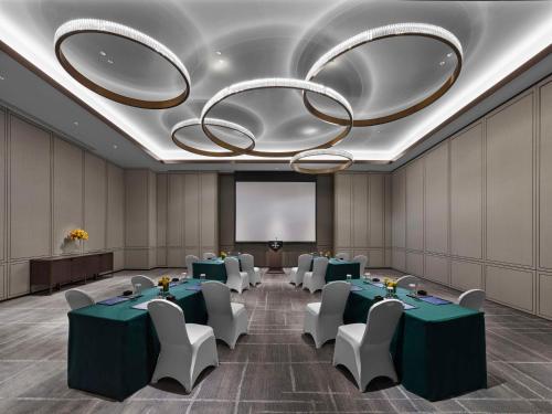 a conference room with green tables and chairs and a large chandelier at Hilton Zhuji in Zhuji