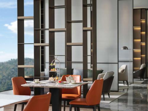 a dining room with a table and chairs and windows at Hilton Zhuji in Zhuji