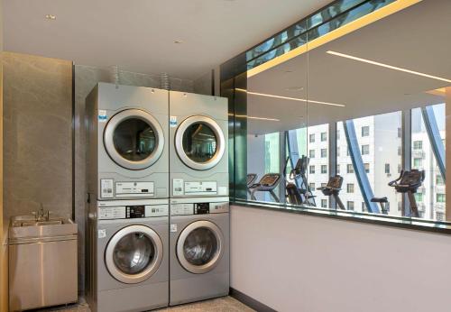a laundry room with three washing machines in it at Hilton Garden Inn Shenzhen Airport,Enjoy 24-hour one way free delivery from hotel to Shenzhen Baoan Airport on the hour in Shenzhen