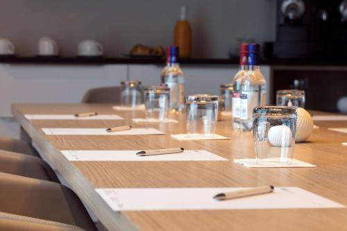 una larga mesa de madera con botellas de vino y copas en Hilton Garden Inn Paris La Villette, en París