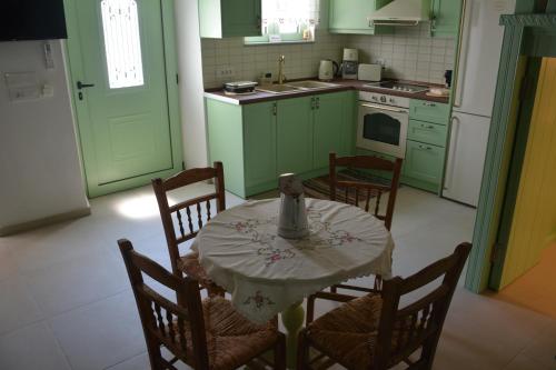 a kitchen with green cabinets and a table and chairs at The Priest's Traditional House Kalithies in Kalithies