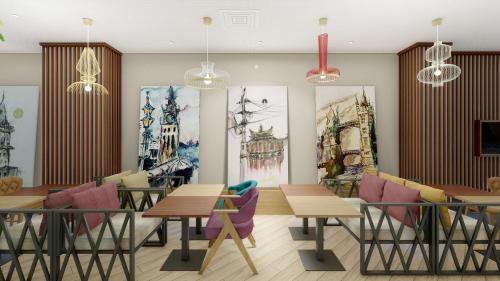 伊斯坦堡的住宿－Hampton By Hilton Istanbul Airport, Arnavutkoy，餐厅设有桌椅,墙上挂有绘画作品