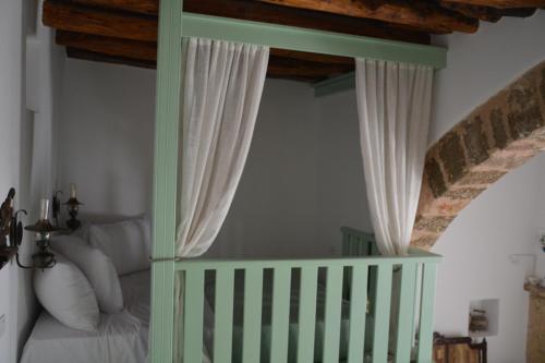 a bedroom with a bed with white curtains and a crib at The Priest's Traditional House Kalithies in Kalithies