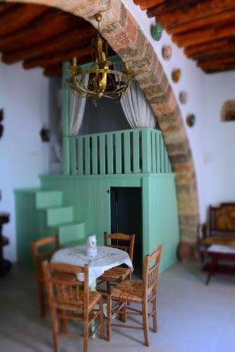 a table and chairs in a room with a green wall at The Priest's Traditional House Kalithies in Kalithies