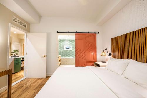 a bedroom with a large white bed and a red door at Embassy Suites By Hilton Orlando Sunset Walk in Kissimmee