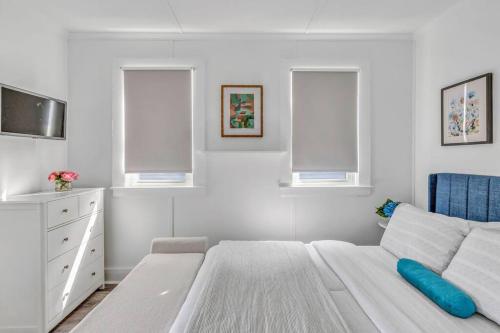 um quarto branco com uma cama e 2 janelas em Lake Cottage Getaway em Portland