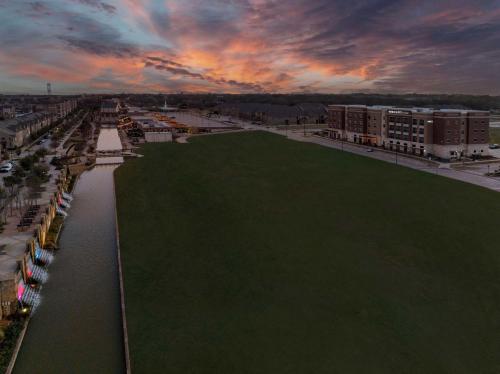 a green field next to a river with a sunset at Home2 Suites By Hilton Flower Mound Dallas in Flower Mound