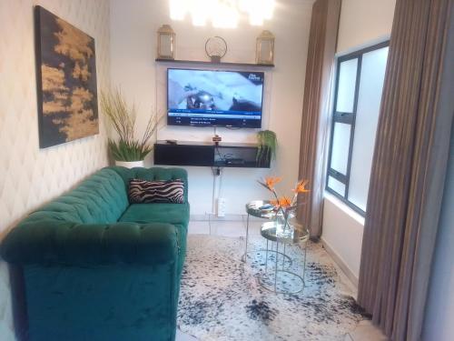 a living room with a green couch and a flat screen tv at Elegant Airbnb in Pretoria