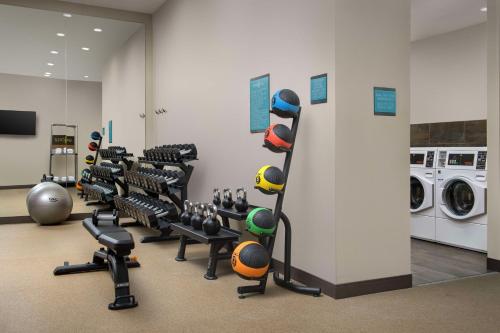 a gym with rows of exercise equipment and a washing machine at Home2 Suites By Hilton Flower Mound Dallas in Flower Mound
