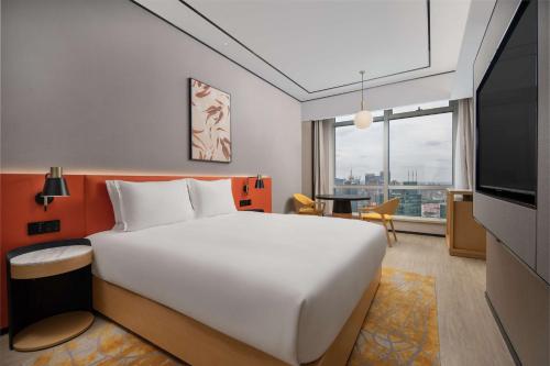 een slaapkamer met een groot wit bed en een televisie bij Hilton Garden Inn Shanghai Lujiazui in Shanghai