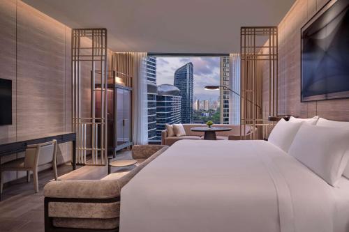una camera con un grande letto bianco e un soggiorno di Conrad Shenzhen, Complimentary mini-bar for first round a Shenzhen