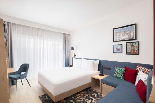 um quarto de hotel com uma cama e um sofá em Hampton By Hilton Targu Mures em Târgu-Mureş