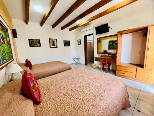 1 dormitorio con 2 camas, TV y escritorio en Los Arrayanes, en Oaxaca City