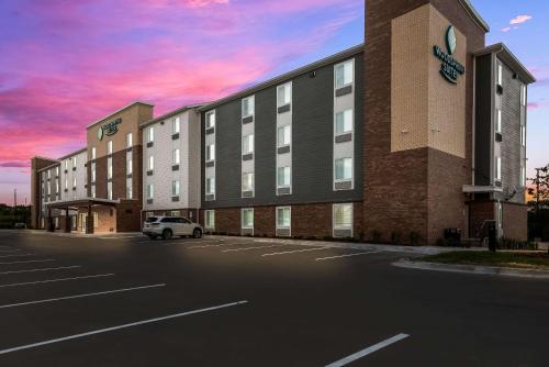 a building with a car parked in a parking lot at WoodSpring Suites Milwaukee - Menomonee Falls in Milwaukee