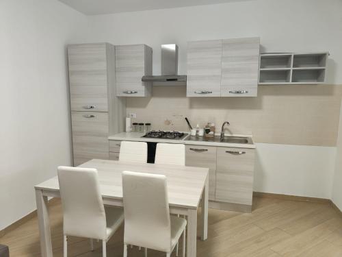una cucina con tavolo in legno e armadietti bianchi di Villa A&M 2 a Latina