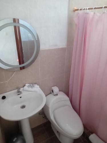 uma casa de banho com um lavatório, um WC e um espelho. em Casa de Alexis em Puerto Baquerizo Moreno