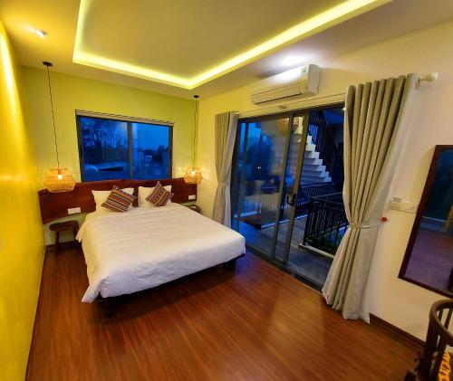 a bedroom with a white bed and a balcony at Hoi An Ti Hon House in Hoi An