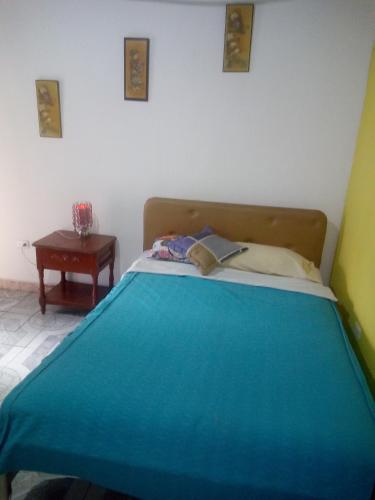 Un dormitorio con una cama azul y una mesa en Hotel Tanta Wasi-Panecillo en Quito