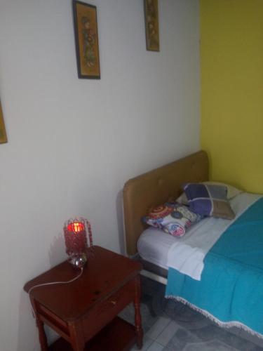 ein Schlafzimmer mit einem Bett und einem Tisch mit einer Lampe in der Unterkunft Hotel Tanta Wasi-Panecillo in Quito