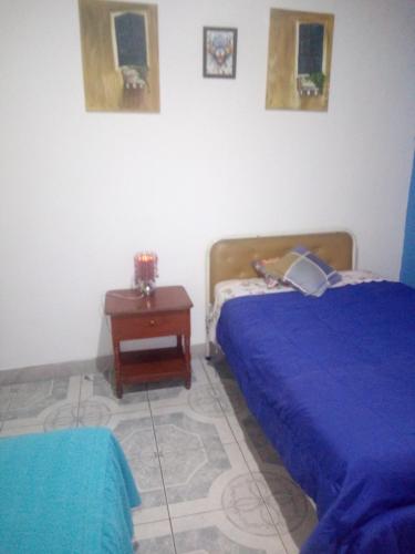 a bedroom with two beds and a night stand with a table at Hotel Tanta Wasi-Panecillo in Quito