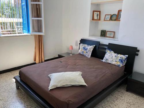 1 dormitorio con 1 cama grande con sábanas y almohadas marrones en Une maison djerbienne en Houmt El Souk